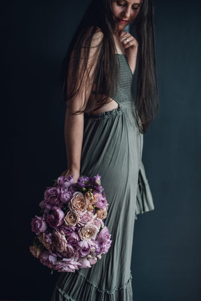 wild-blossoms-bouquet-styles-dresses-web-70 women in grey dress holding a dusty pink rose bouquet at her hip