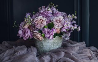 pink, purple and blush centerpiece in a grey ceramic container in a pile of fig color silk
