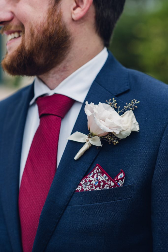 wild-blossoms-brett-cherokee-ranch-web-44 groom in navy suit and red tie with white boutonniere