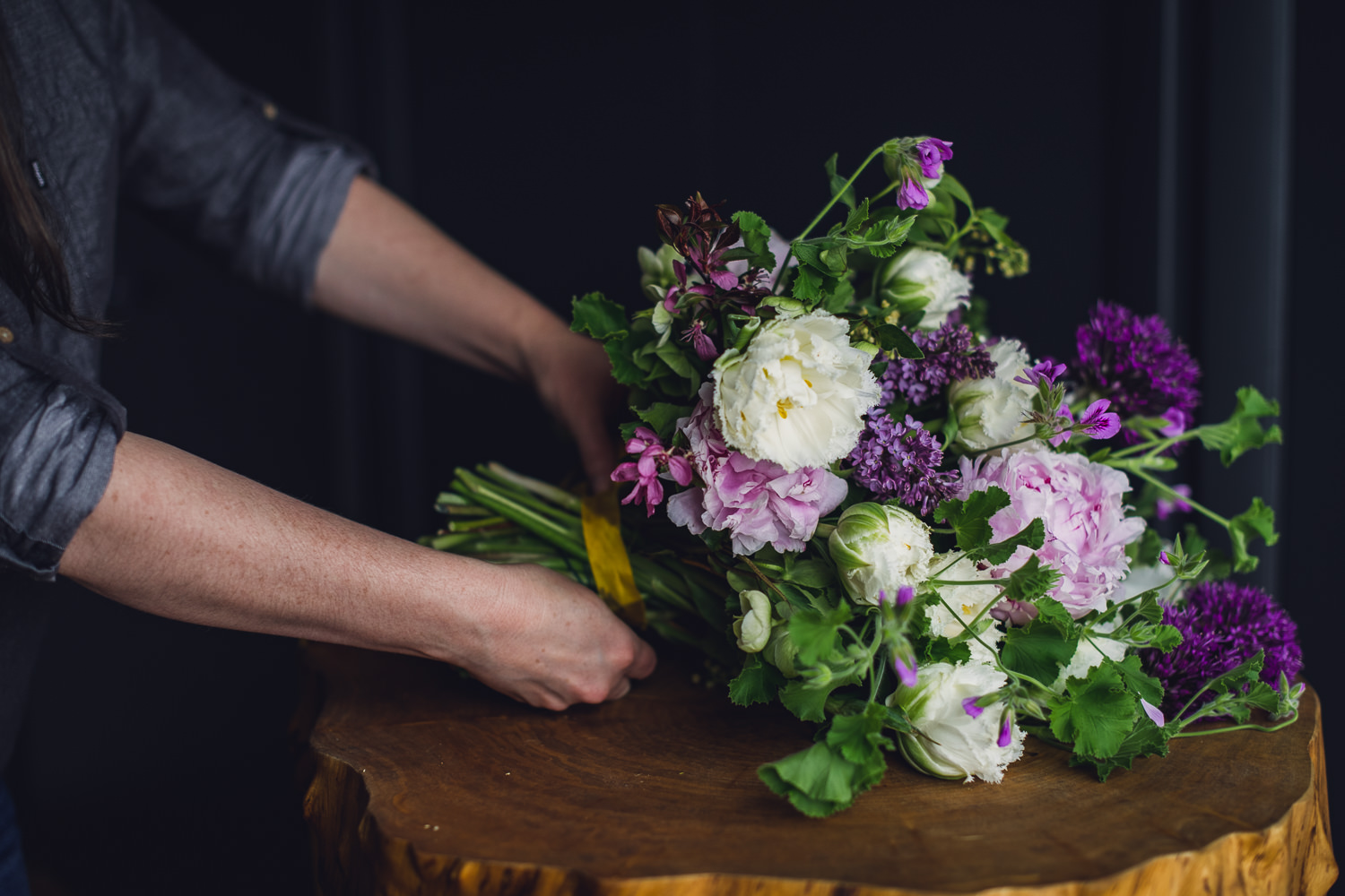 websize-8829 woman tying ribbon onto a white, pink and purple spring bouquet