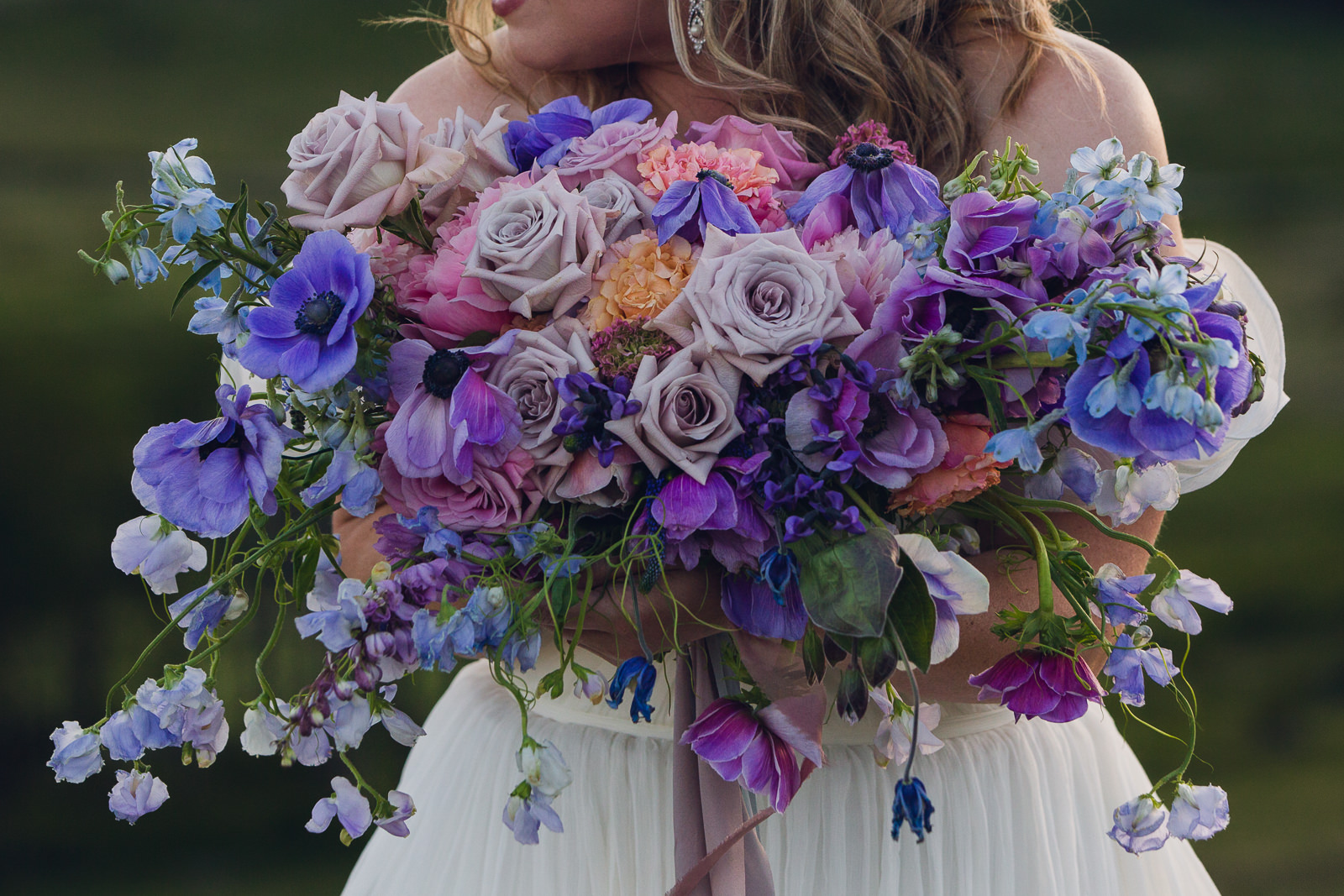 melody-bouquet-web-2 bride holding bouquet of purple anemones, roses, delphinium, sweet pea